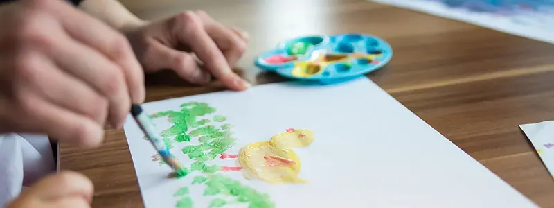 Vuxen som hjälper barn måla