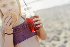 Flicka på stranden med saft och kaka
